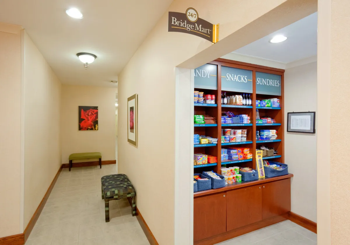 A convenient snack shelf stocked with a variety of treats, adjacent to bench seating and cheerful artwork. The area offers guests a spot to grab quick snacks or enjoy a casual bite, emphasizing flexibility and convenience for longer stays.