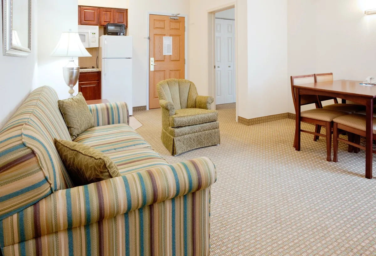 The image shows a warm, inviting living area with a striped sofa, a comfortable armchair, and a dining table set for gathering. The space is cozy and well-lit, ideal for relaxing, socializing, playing games, and enjoying meals together. The furnishings suggest a homey atmosphere, perfect for unwinding after exploring Durham or nearby campuses.
