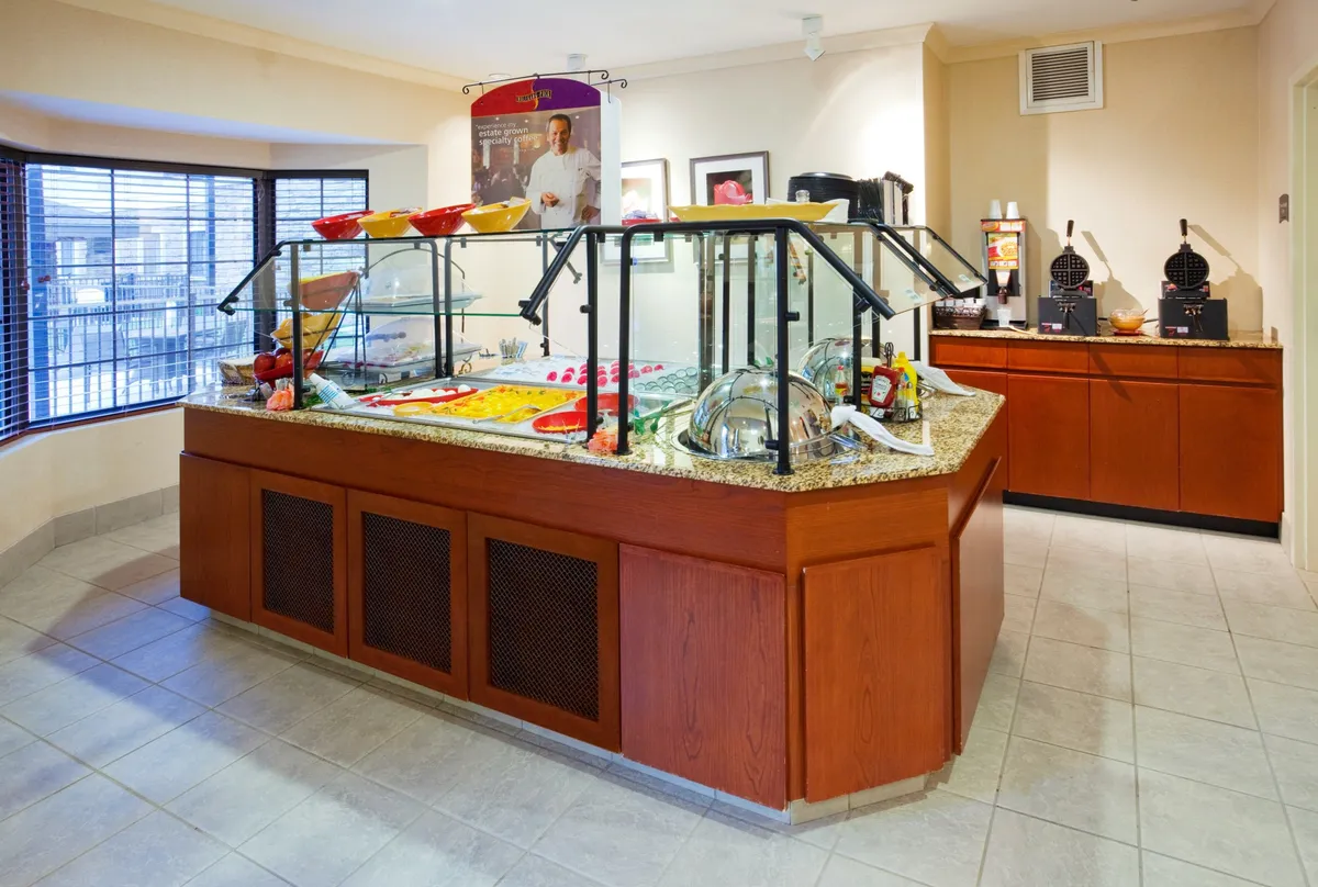 A vibrant breakfast buffet station featuring a tempting spread of food in decorative bowls, a dedicated coffee station, and an inviting setup for guests to enjoy their morning meal. The counter is well-organized, offering both hot and cold selections, with a bright and cheerful atmosphere that encourages socializing and a fresh start to the day.
